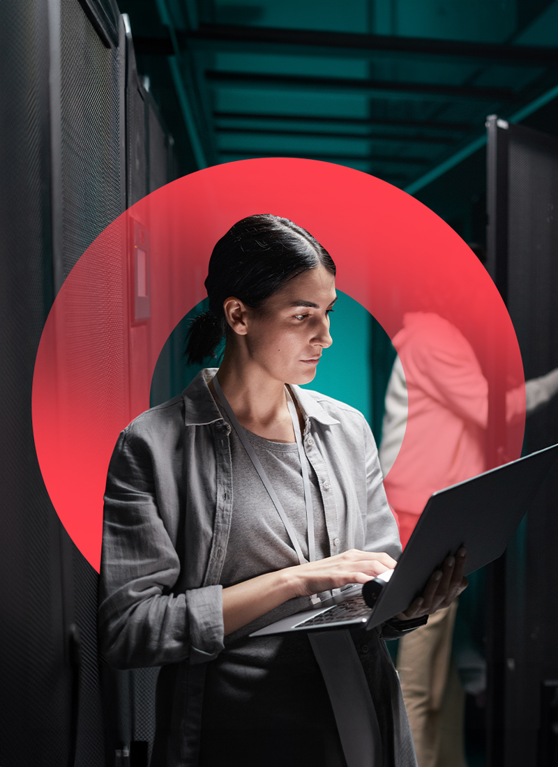 Woman standing and holding laptop, while typing on laptop