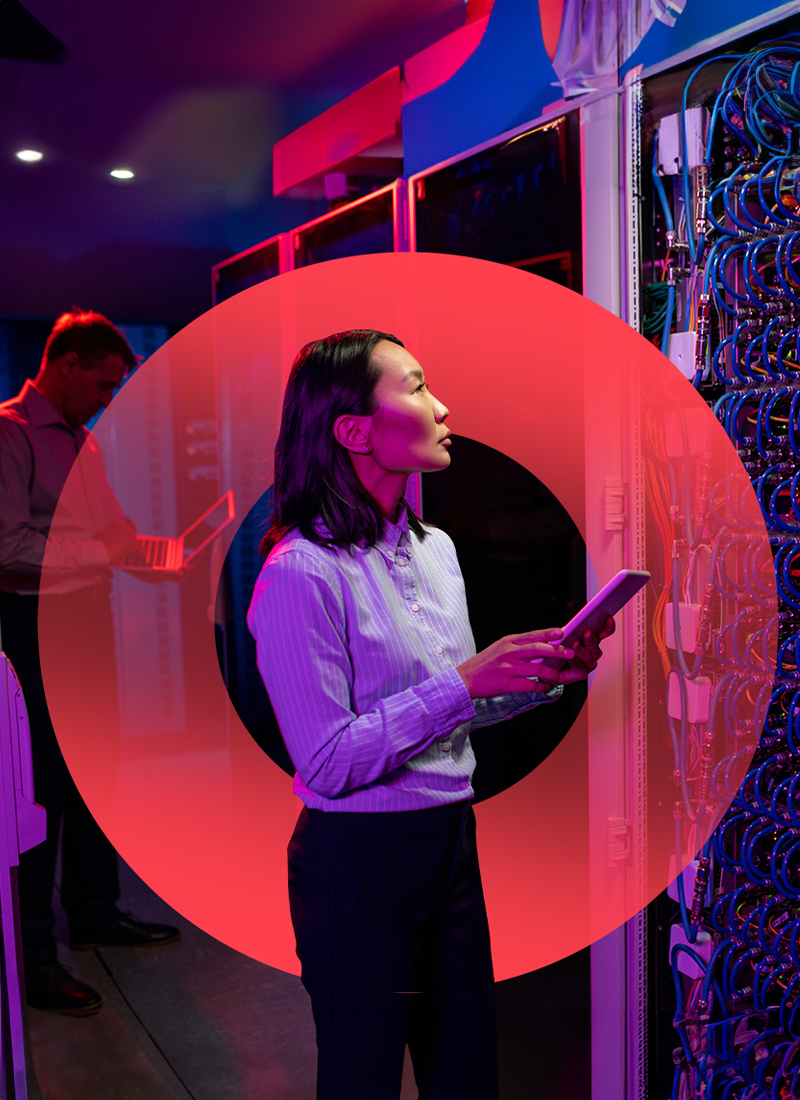 Women standing in a computer room looking upward while holding tablet