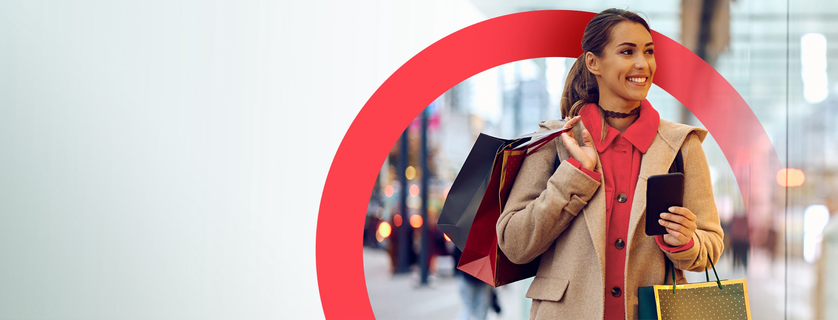 Smiling woman holding a cell phone with a shopping bag over her shoulder, symbolizing a satisfied shopper using mobile shopping solutions.