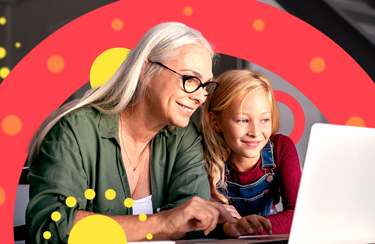 An elderly woman and a young girl looking at a laptop, smiling