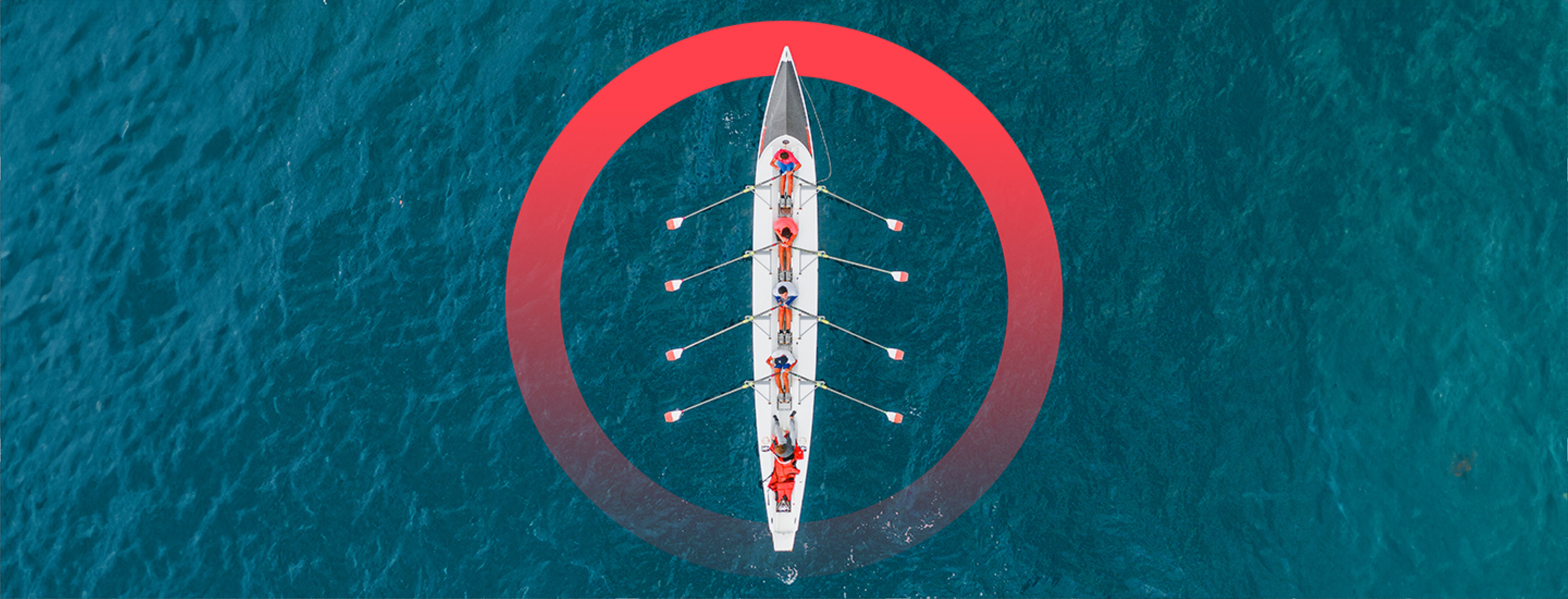 A bird's-eye view of a five-person rowing team in a racing row boat surrounded by water.