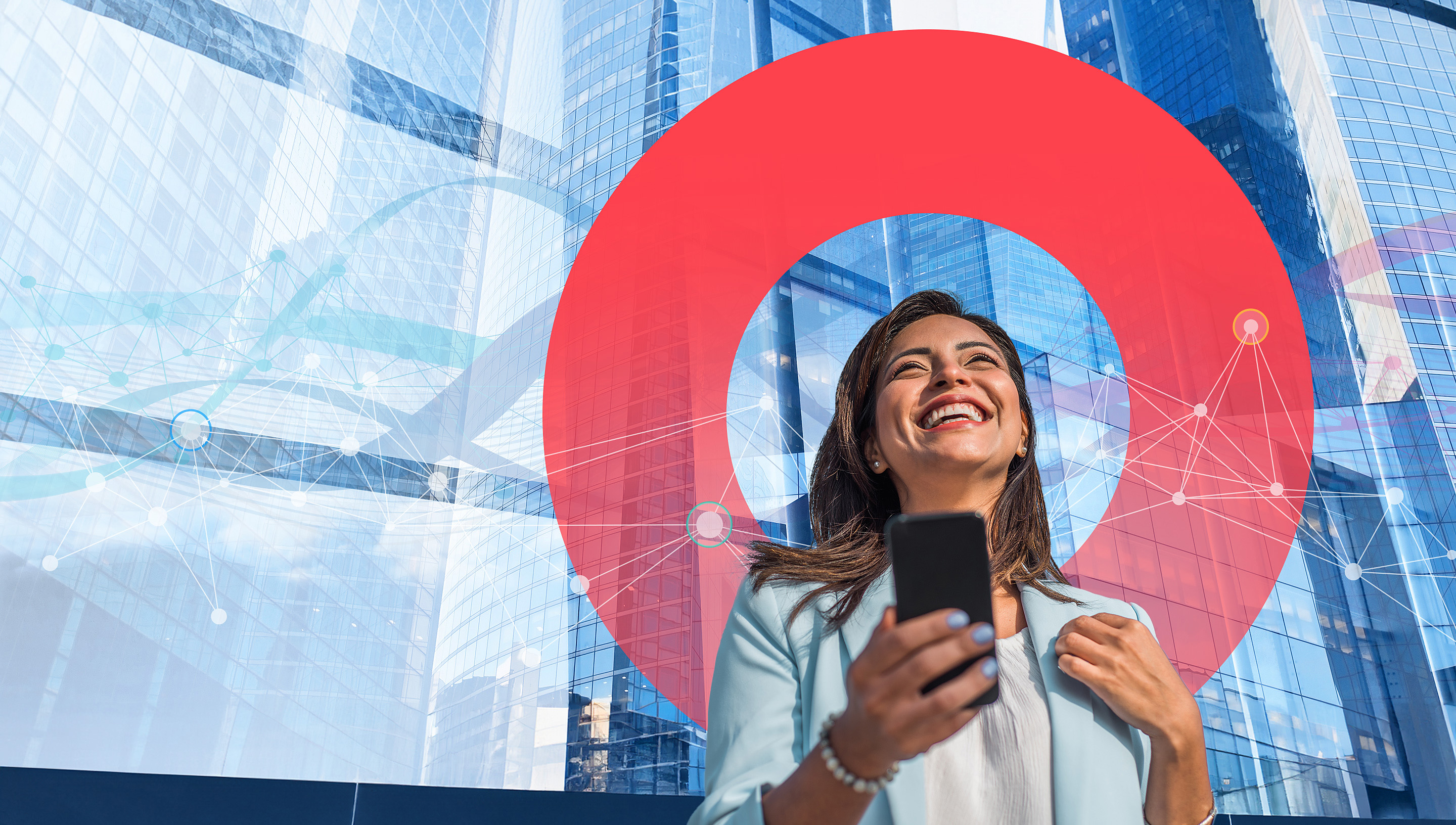 A businesswoman holds her mobile phone, talking and laughing while standing in front of a modern office building.